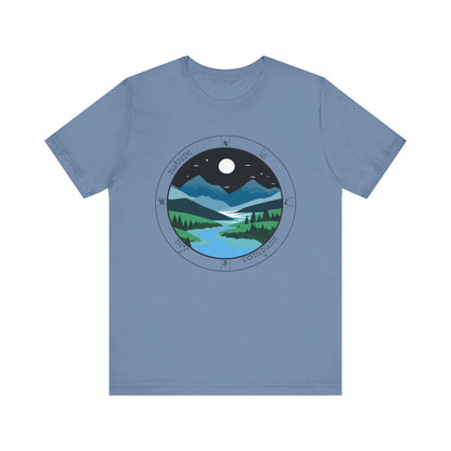 Blue t-shirt with a circular design of a night scene with mountains and a moon on a white background